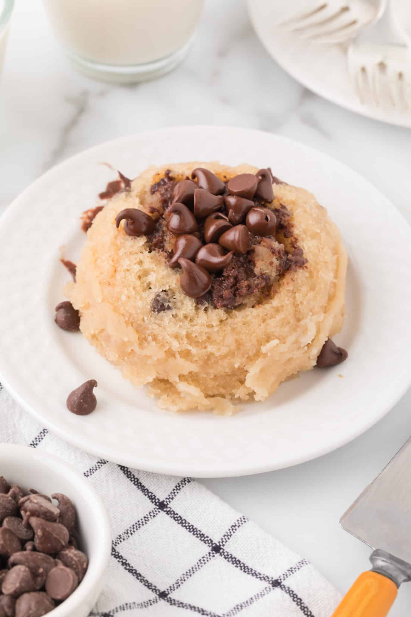 vanilla mug cake served on plate topped with chocolate chips.