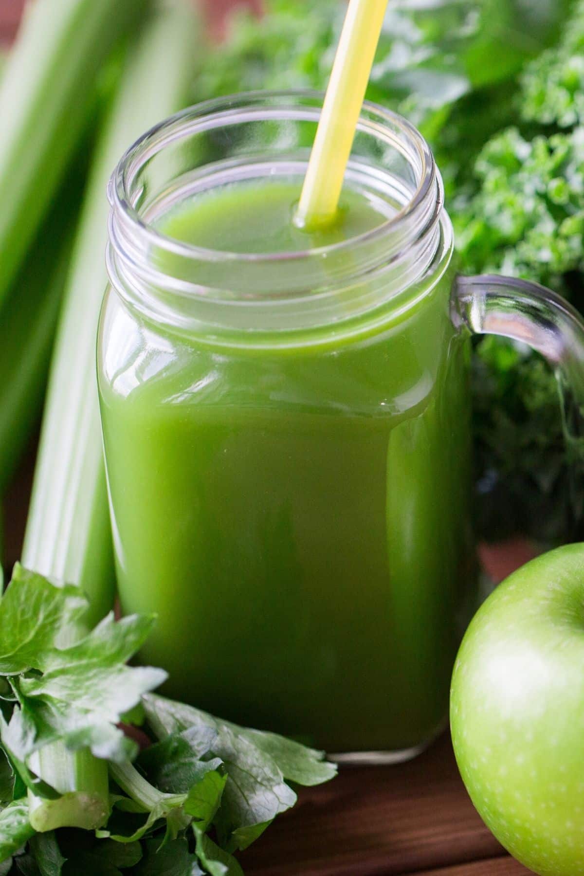 green juice in glass with straw.