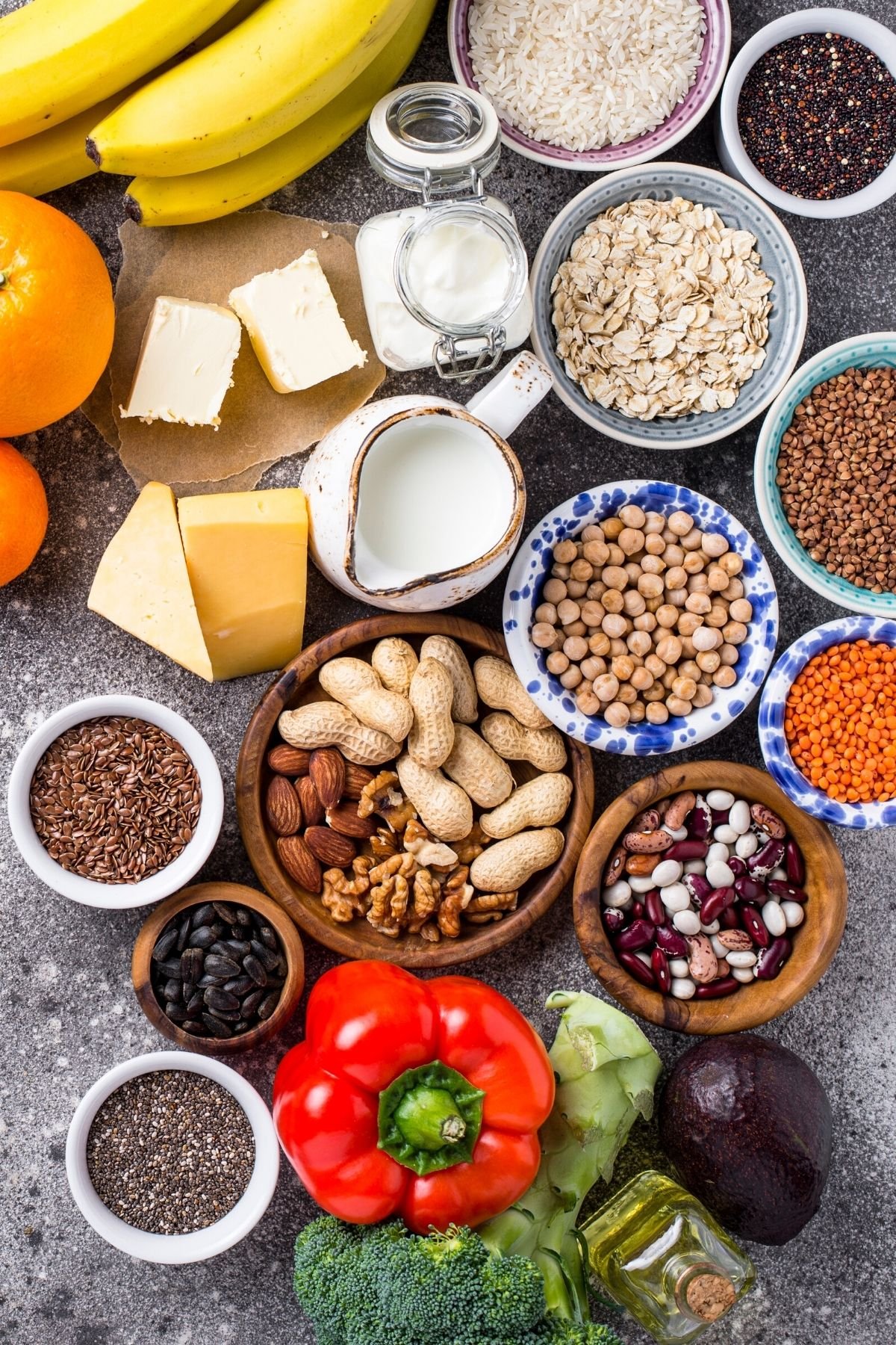 Bowls of nuts, beans, lentils, and seeds on a table.