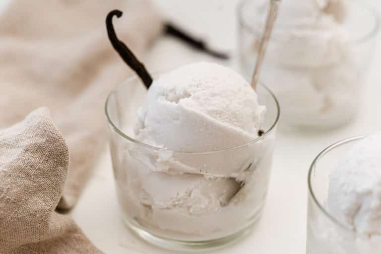 Homemade vanilla ice cream and vanilla bean in a glass cup.