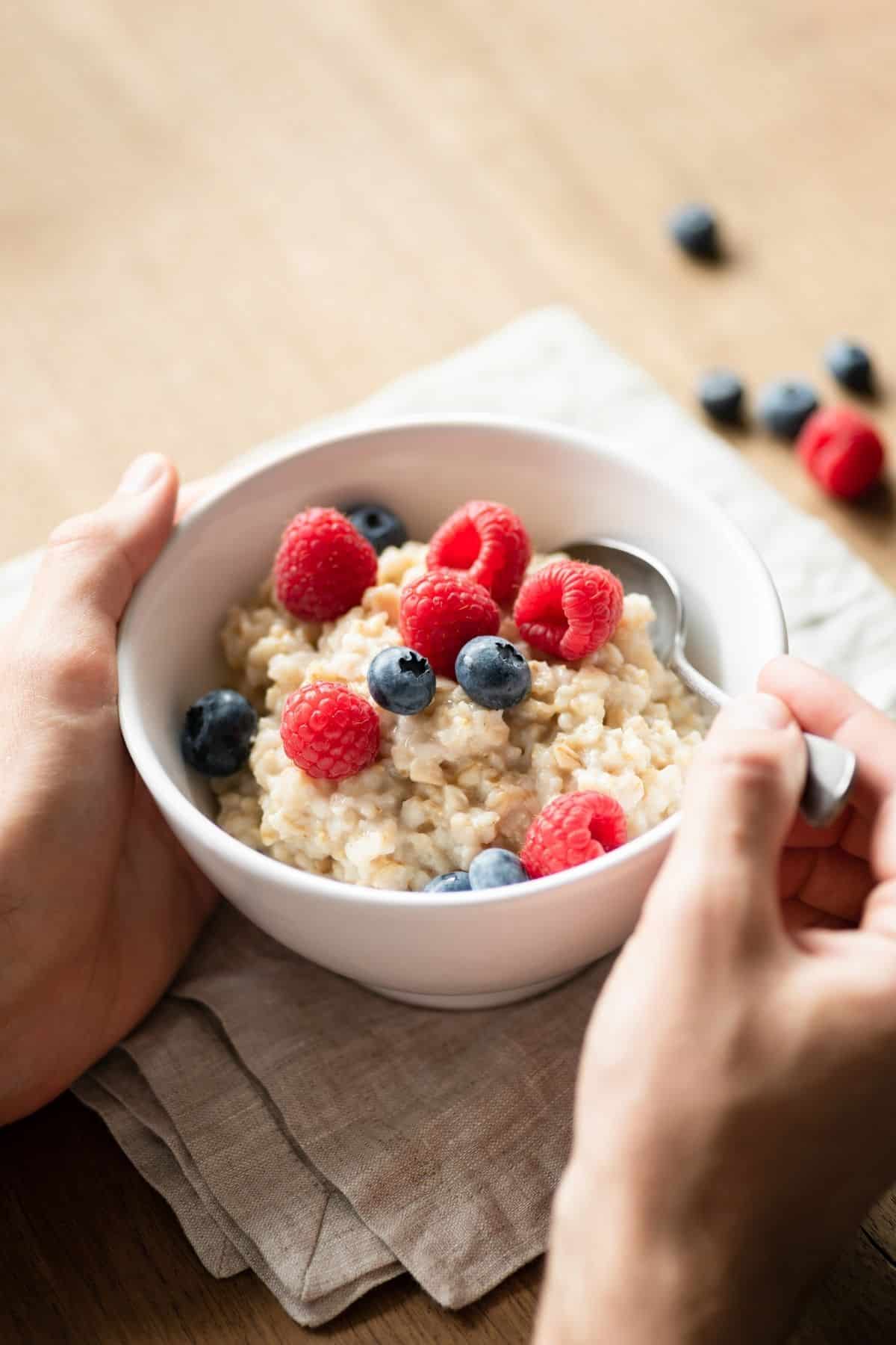 A bowl of oatmeal with berries on it.