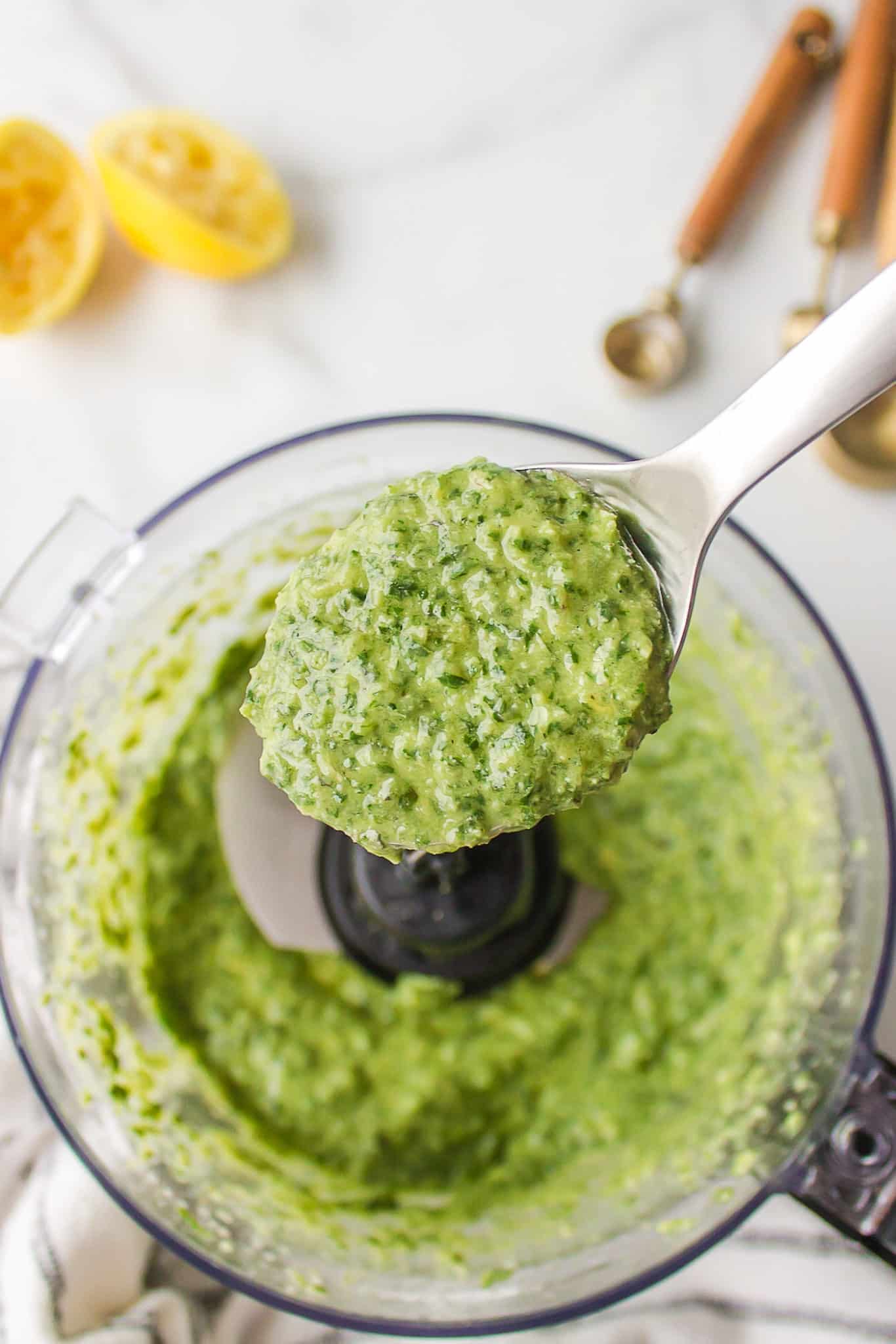 dairy-free pesto sauce made in a food processor and shown on a spoon.