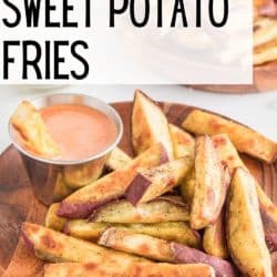 Sweet potato fries and a silver bowl of dip on a wooden plate.