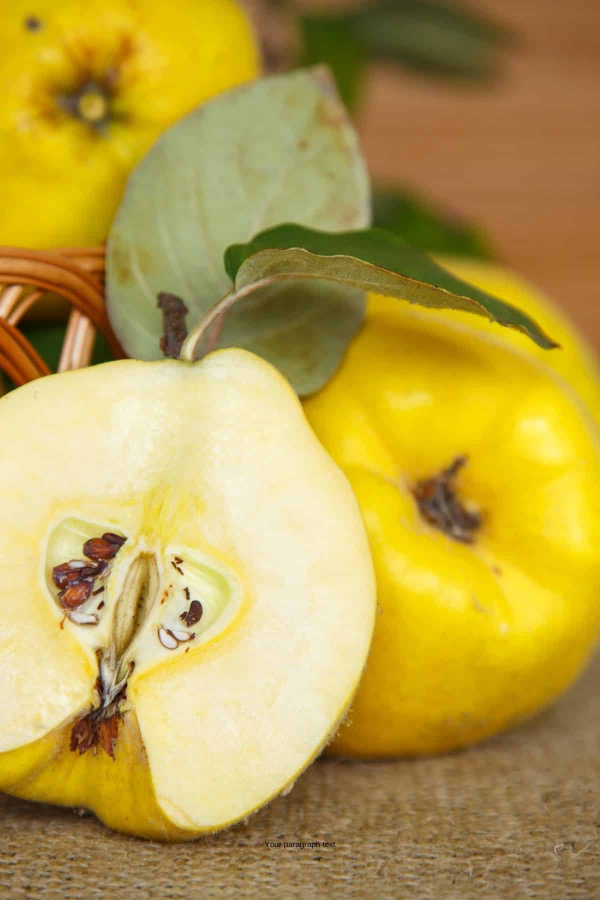 Quince fruit cut in half with whole fruit behind it.