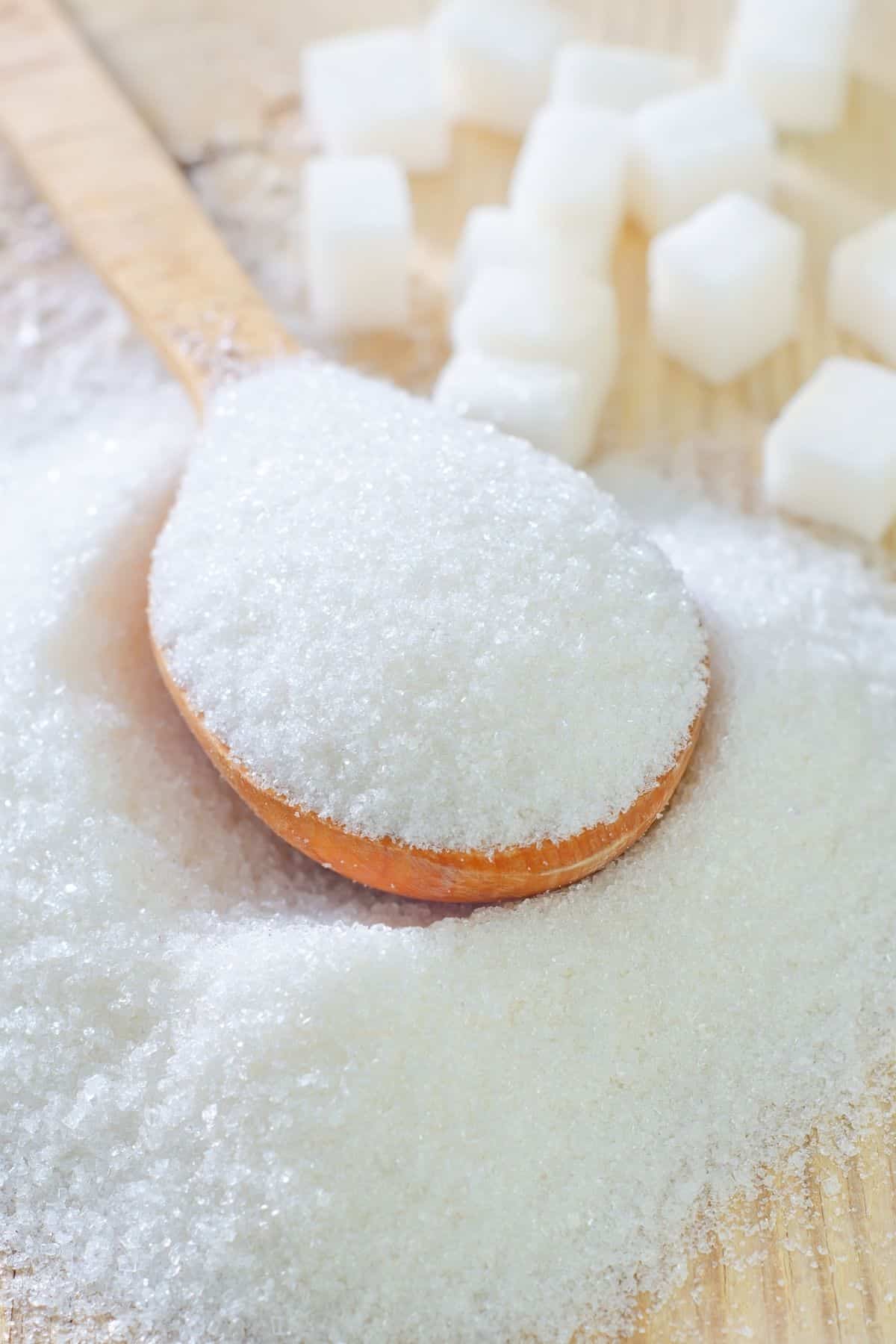 Close up of sugar on a wooden spoon.