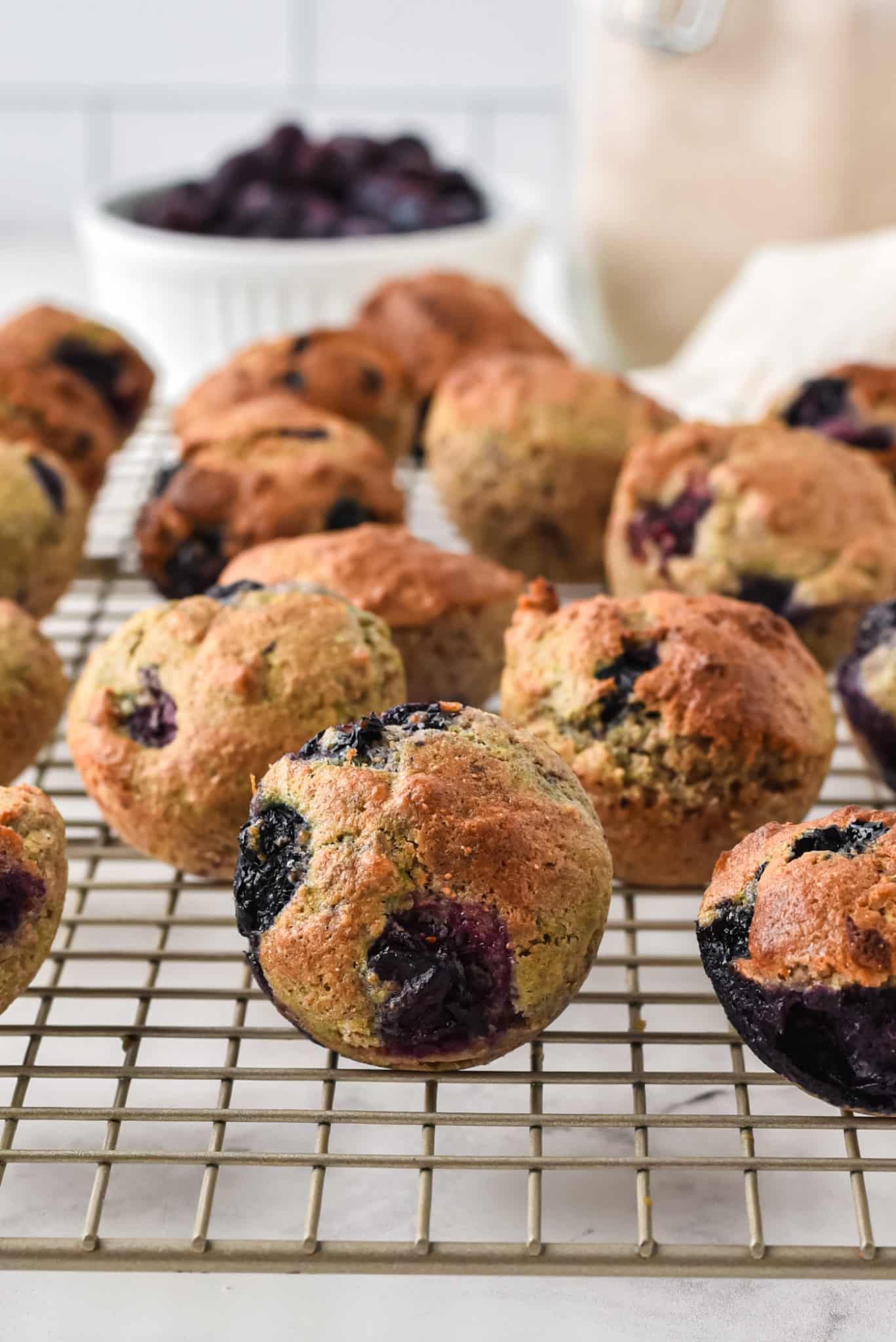Mini blueberry muffins set out on a wire cooling rack.