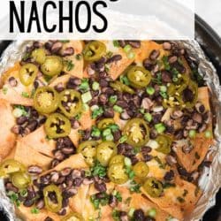 Air fryer nachos in an air fryer basket, topped with black beans and jalapenos.