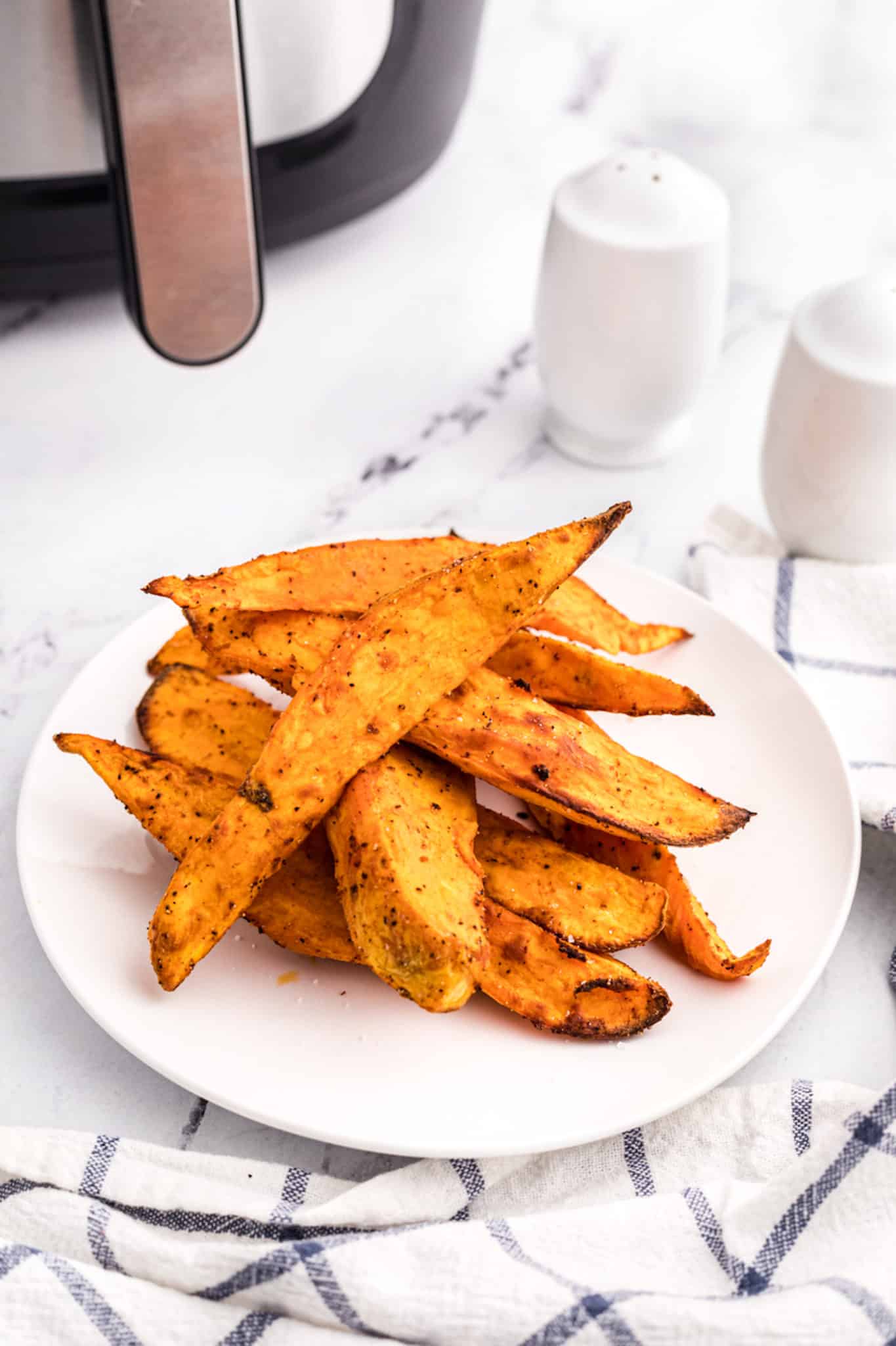 Air fried sweet potato wedges on a white plate.