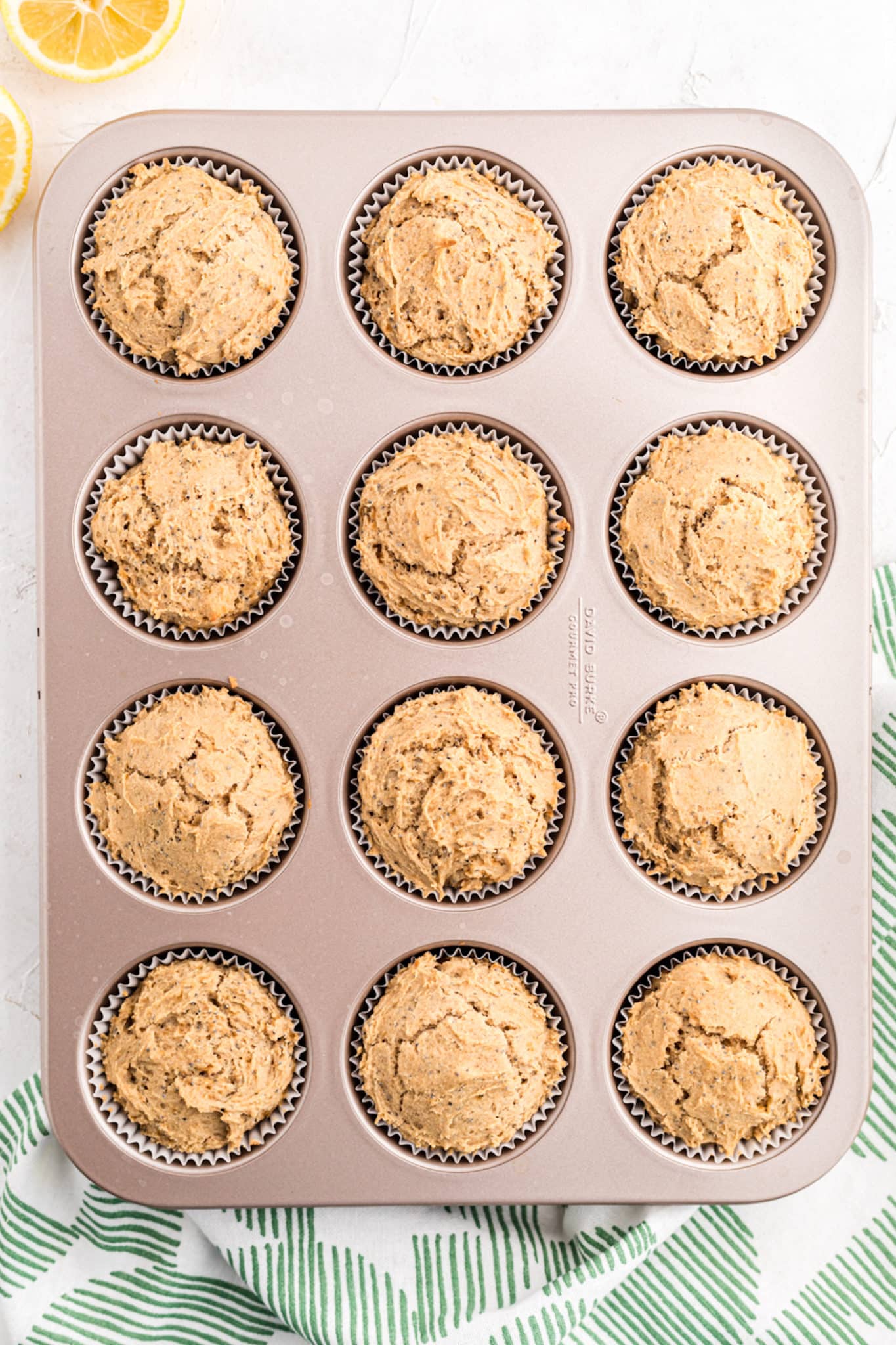 Top view of baked vegan lemon poppy seed muffins in a metal muffin pan.