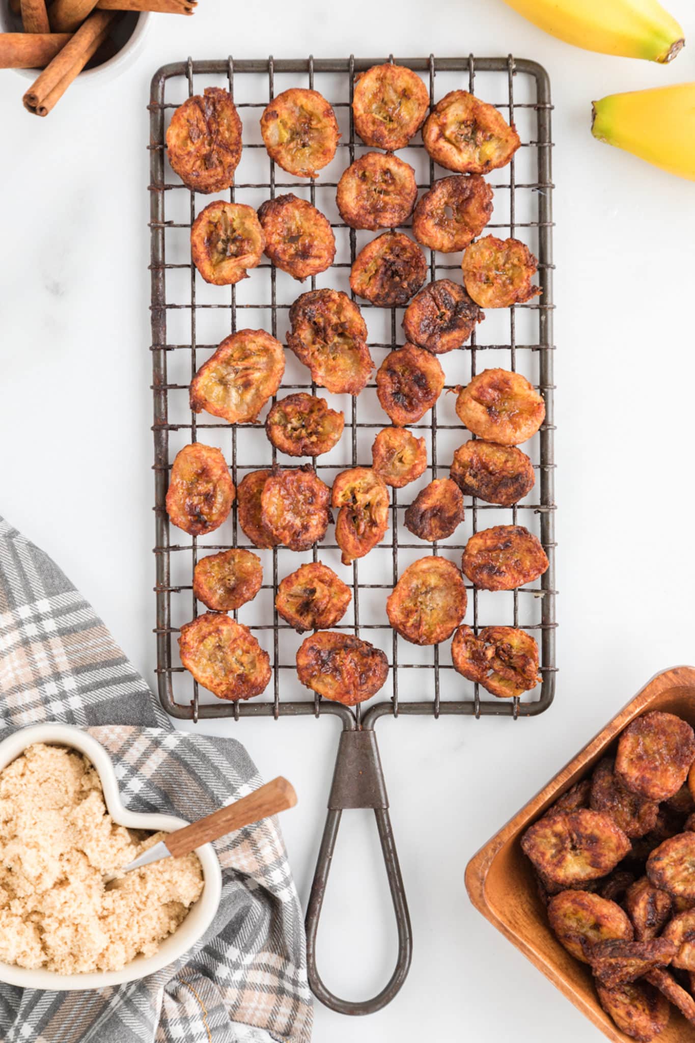 Air fryer cinnamon banana chips on a cooling rack on a white counter.