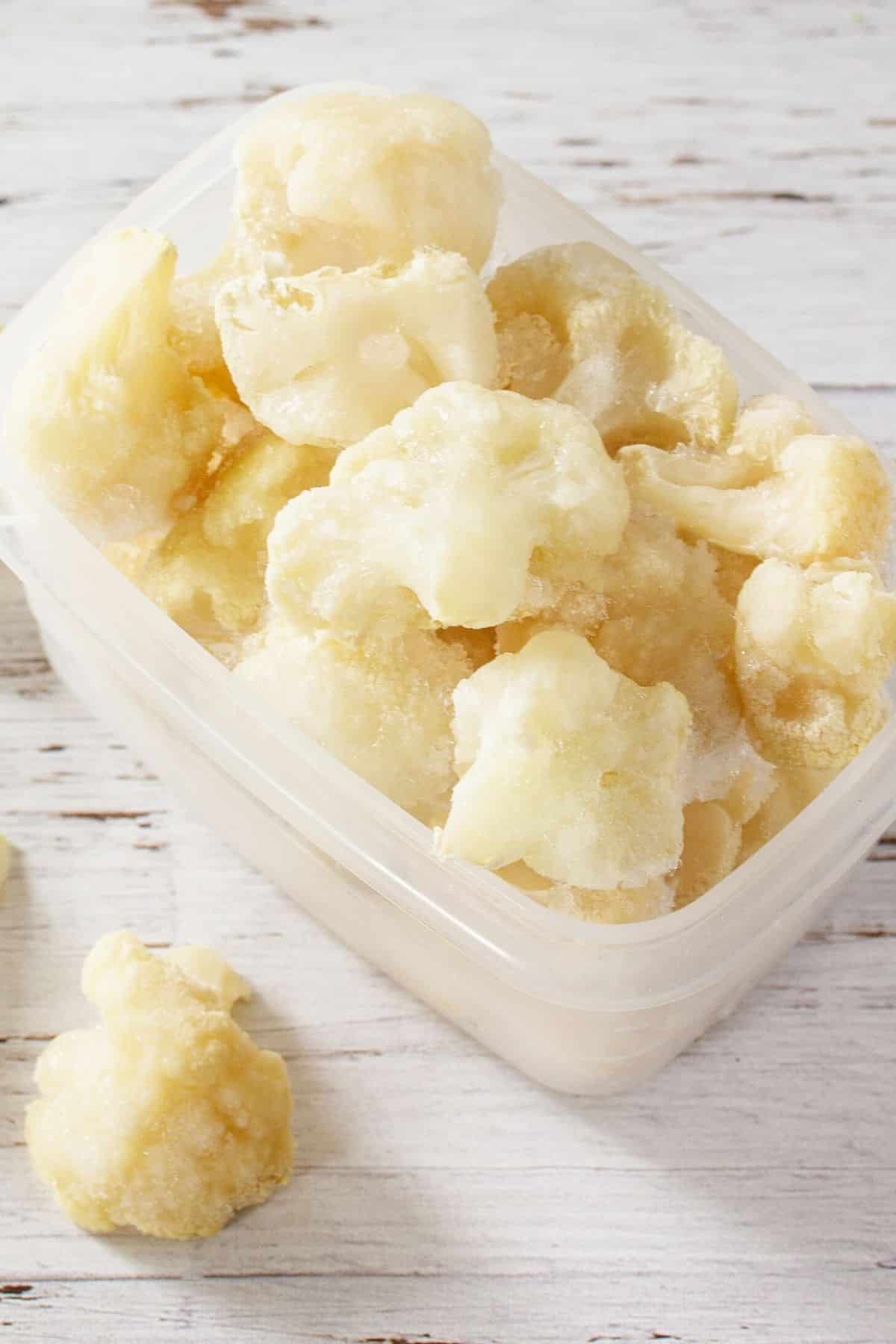 container of frozen cauliflower florets on a tabletop.