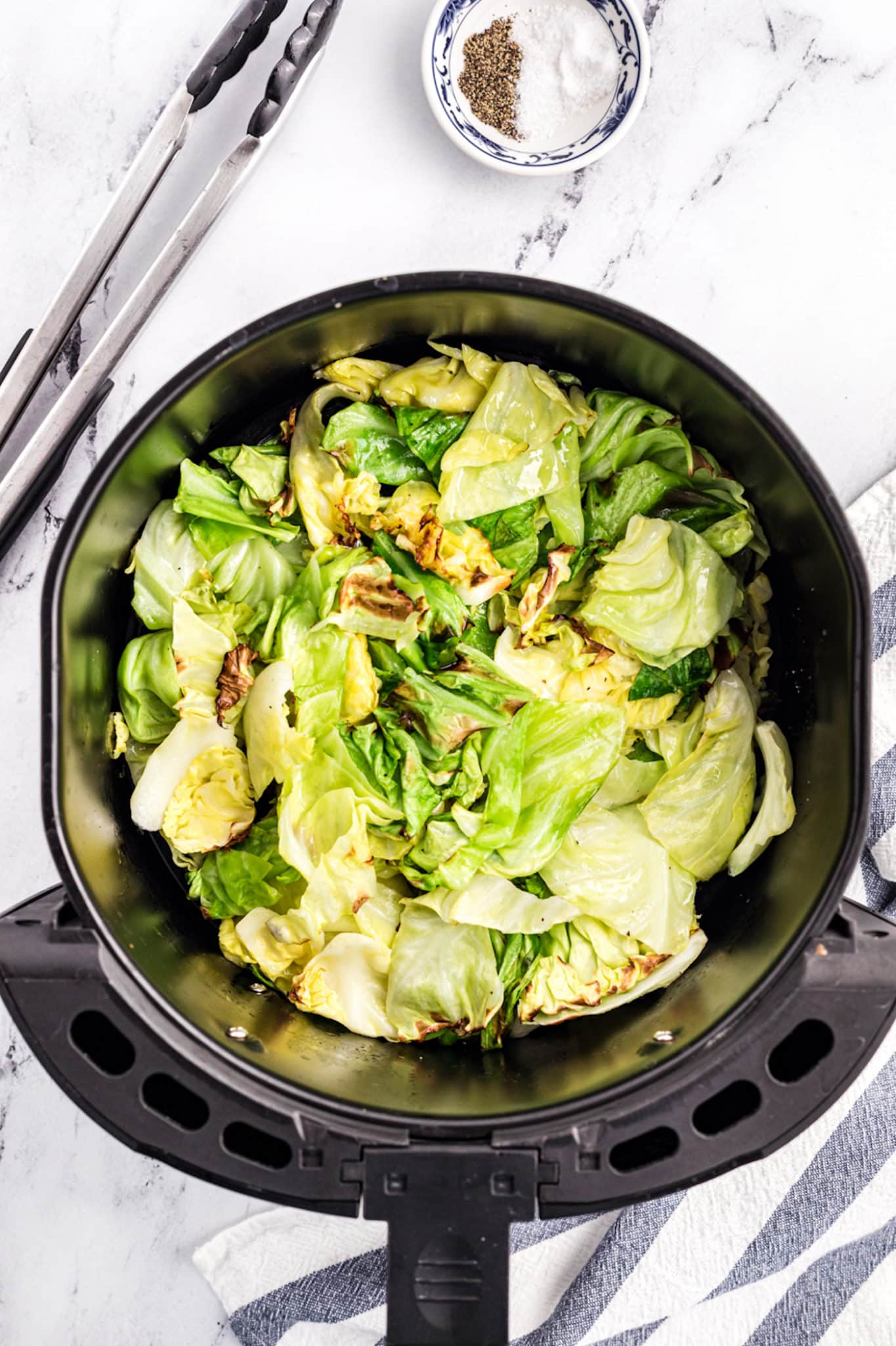 Cooked cabbage in an air fryer basket.