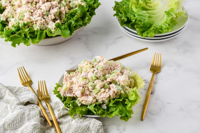 Chicken salad on a bed of greens on a white plate.