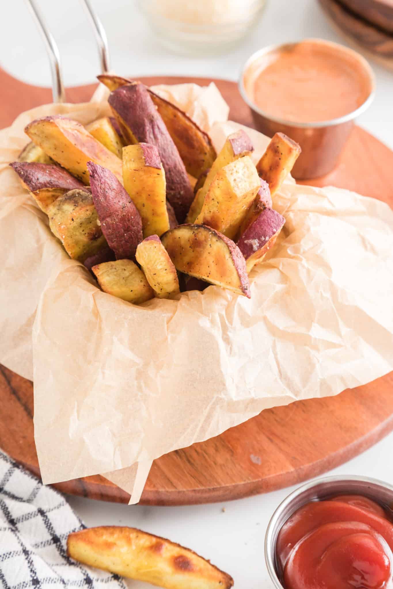 baked japanese sweet potato fries served in a basket with dipping sauces.