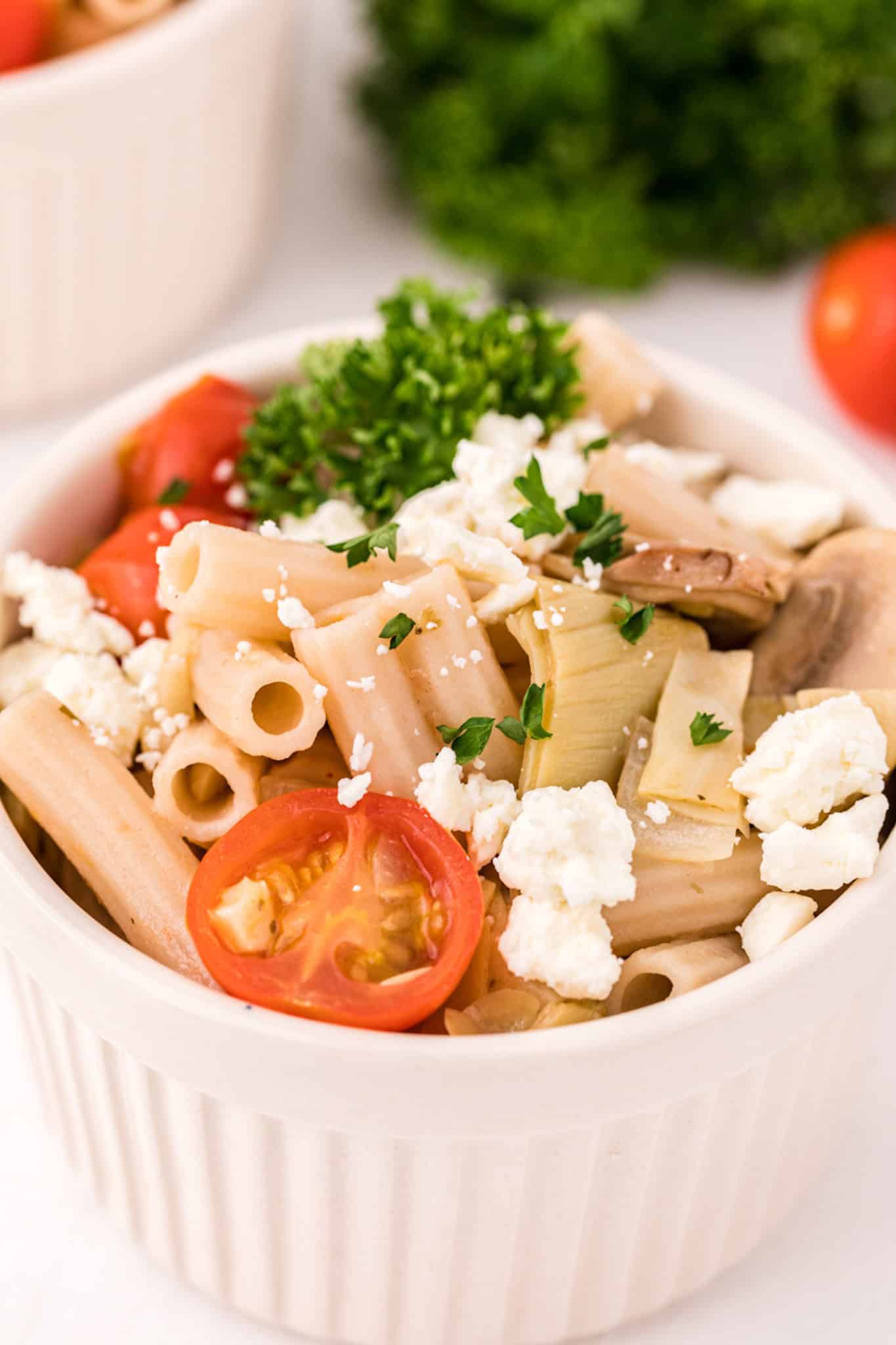 bowl of gluten-free pasta salad with cheese, tomatoes, and parsley