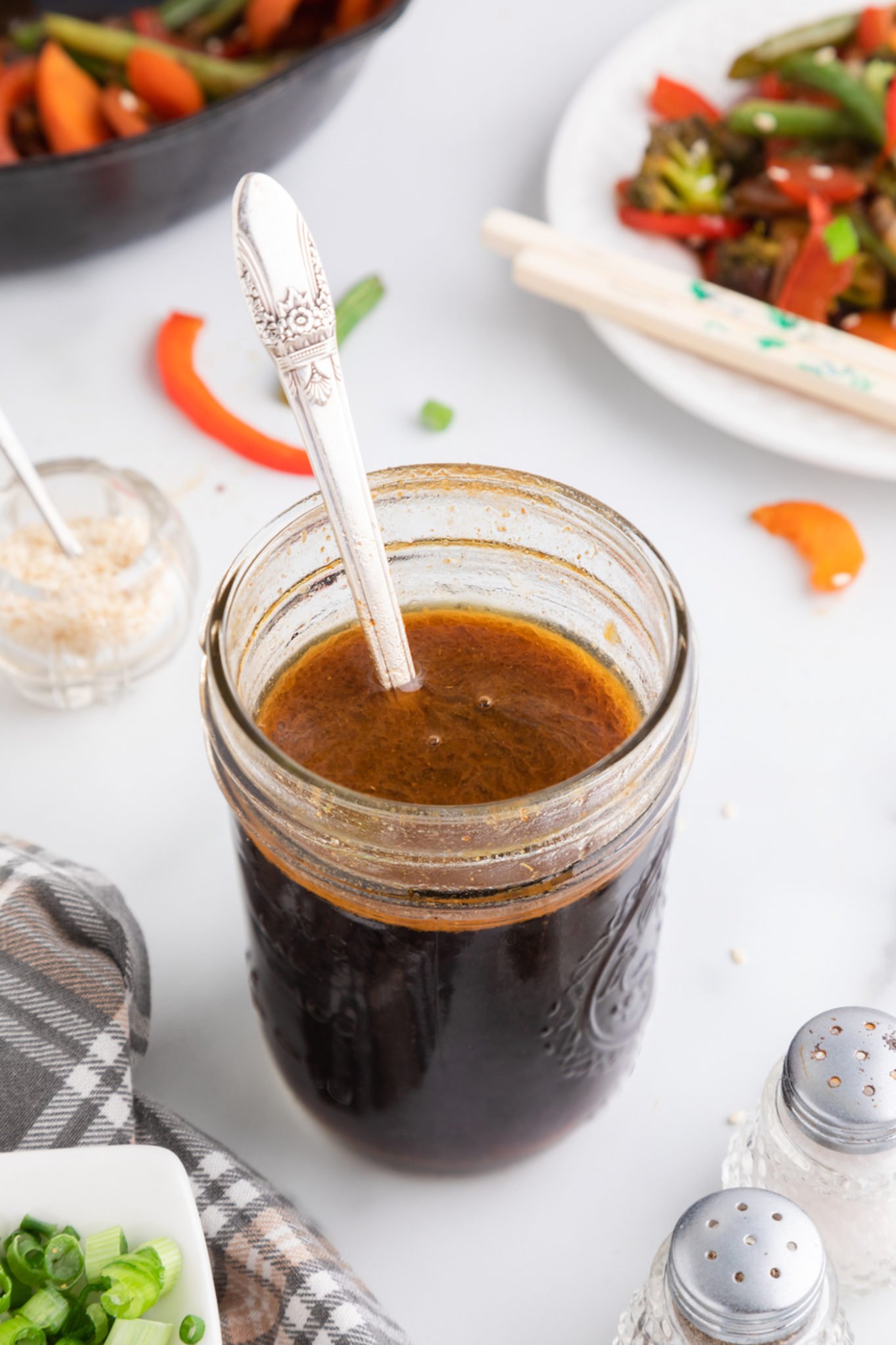 A silver spoon in a jar of freshly made stir fry sauce.
