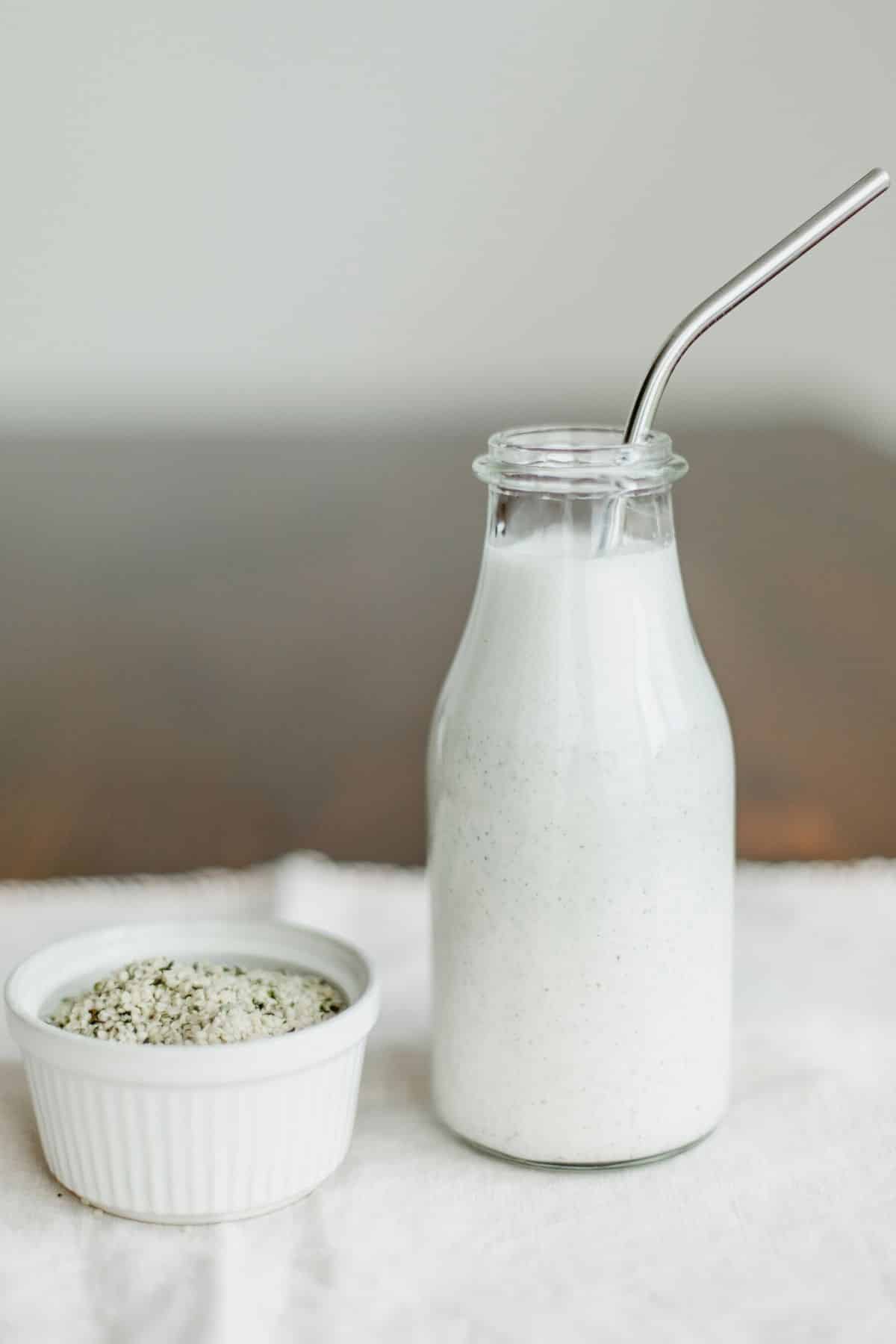 vanilla hemp milk in tall jar with stainless steel straw.