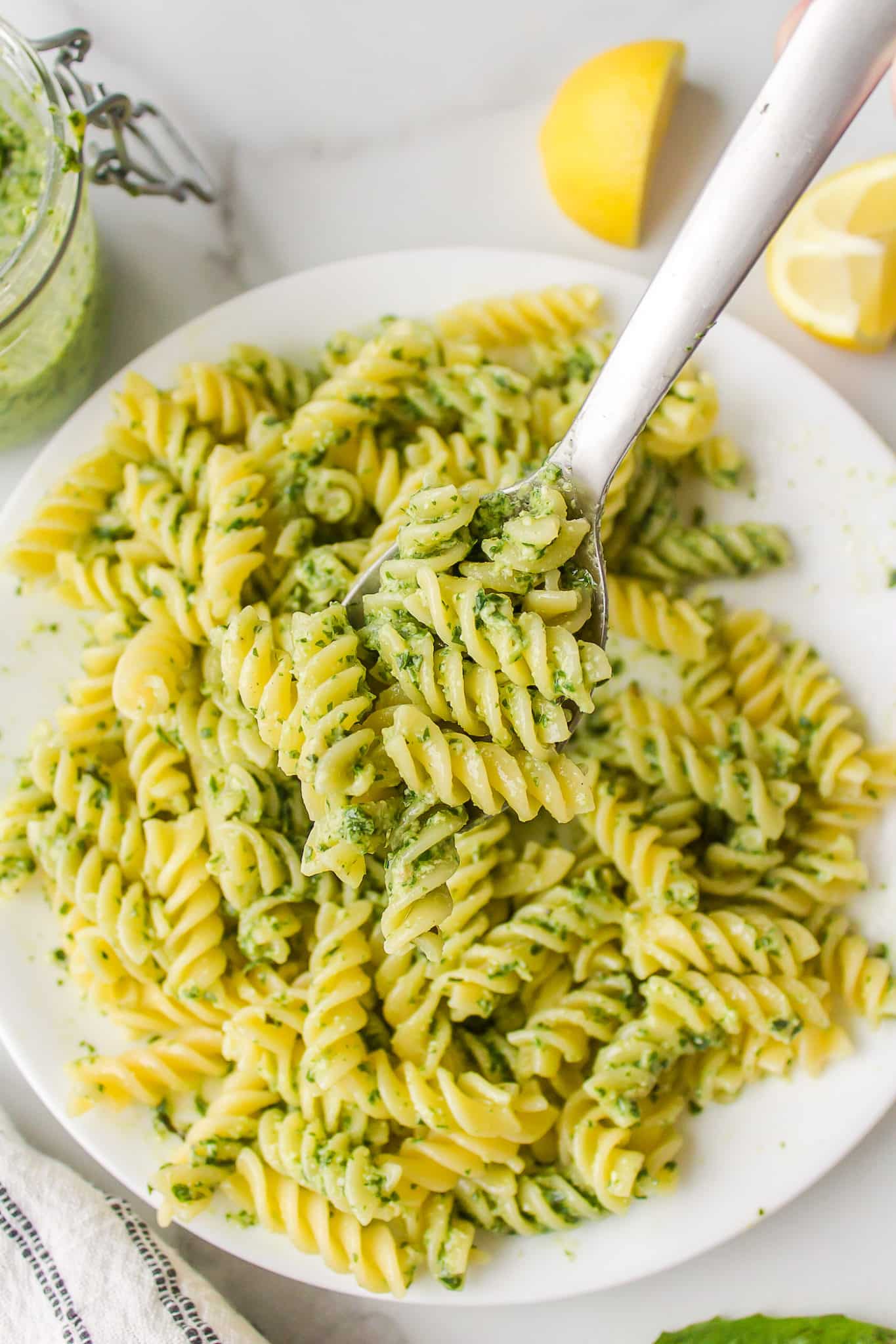 bowl of pesto pasta with a spoon ready to eat.