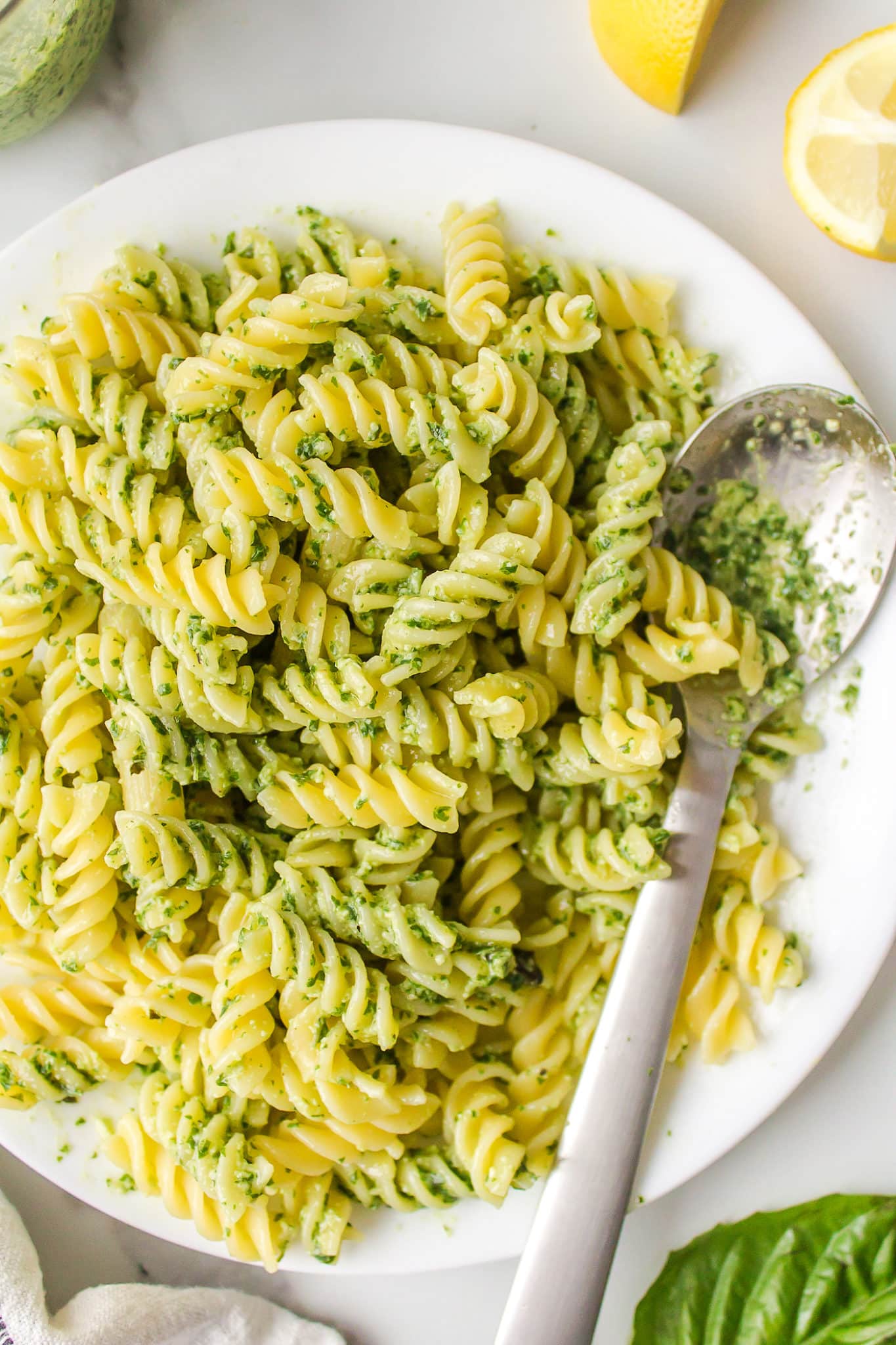 Dairy free pesto mixed with rotini in a large white bowl.