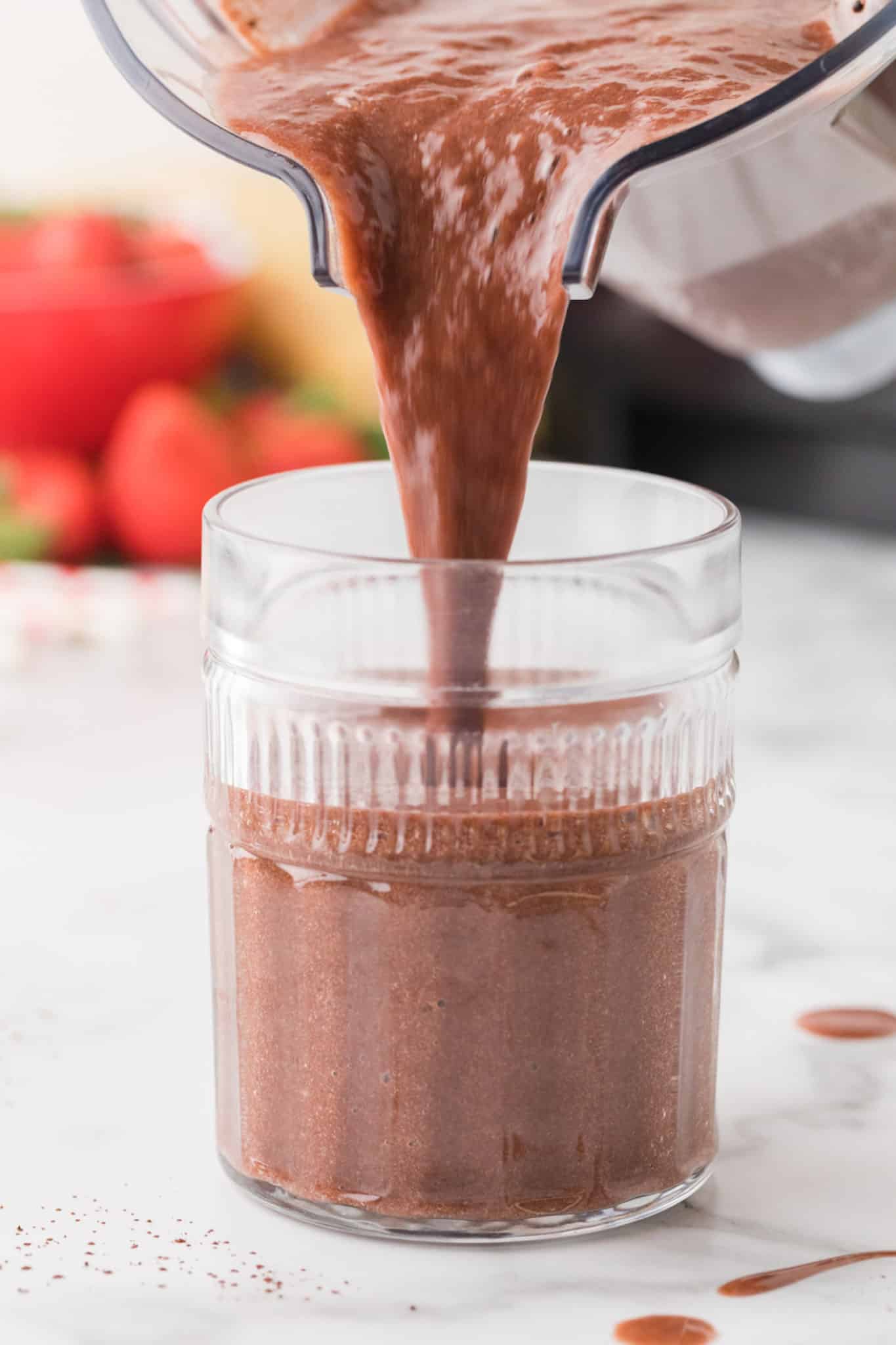pouring chocolate smoothie into a glass.