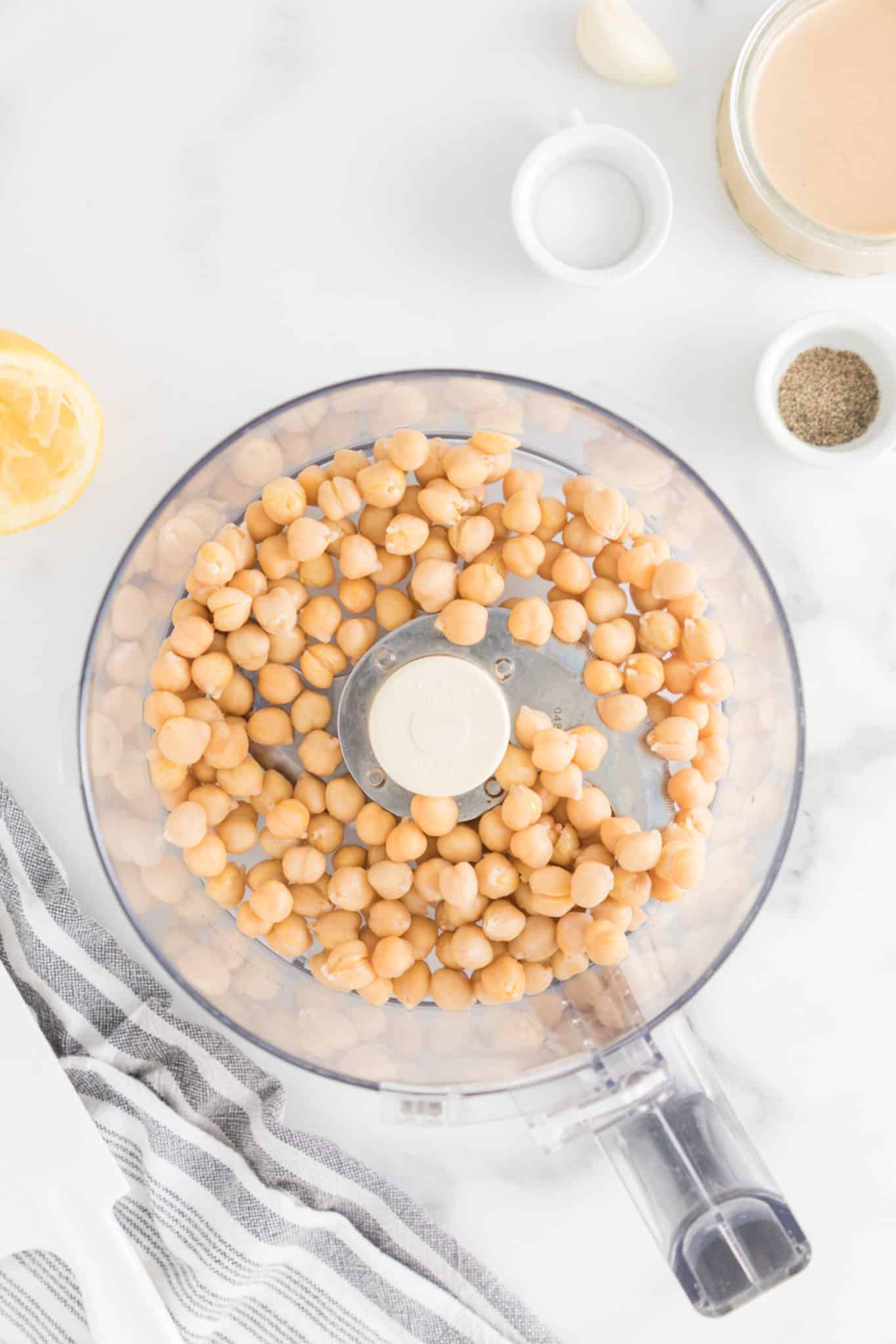 Canned chickpeas, drained and rinsed, in the bowl of a food processor.