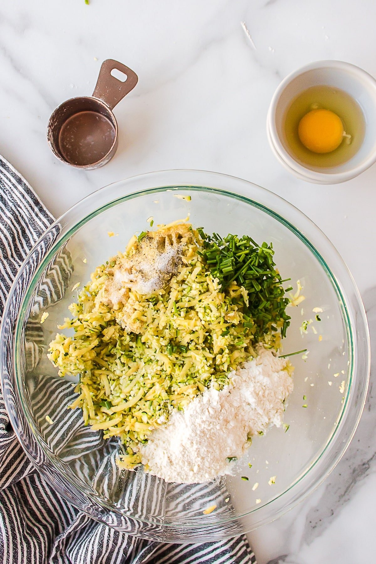 making zucchini potato fritters in bowl mixture.