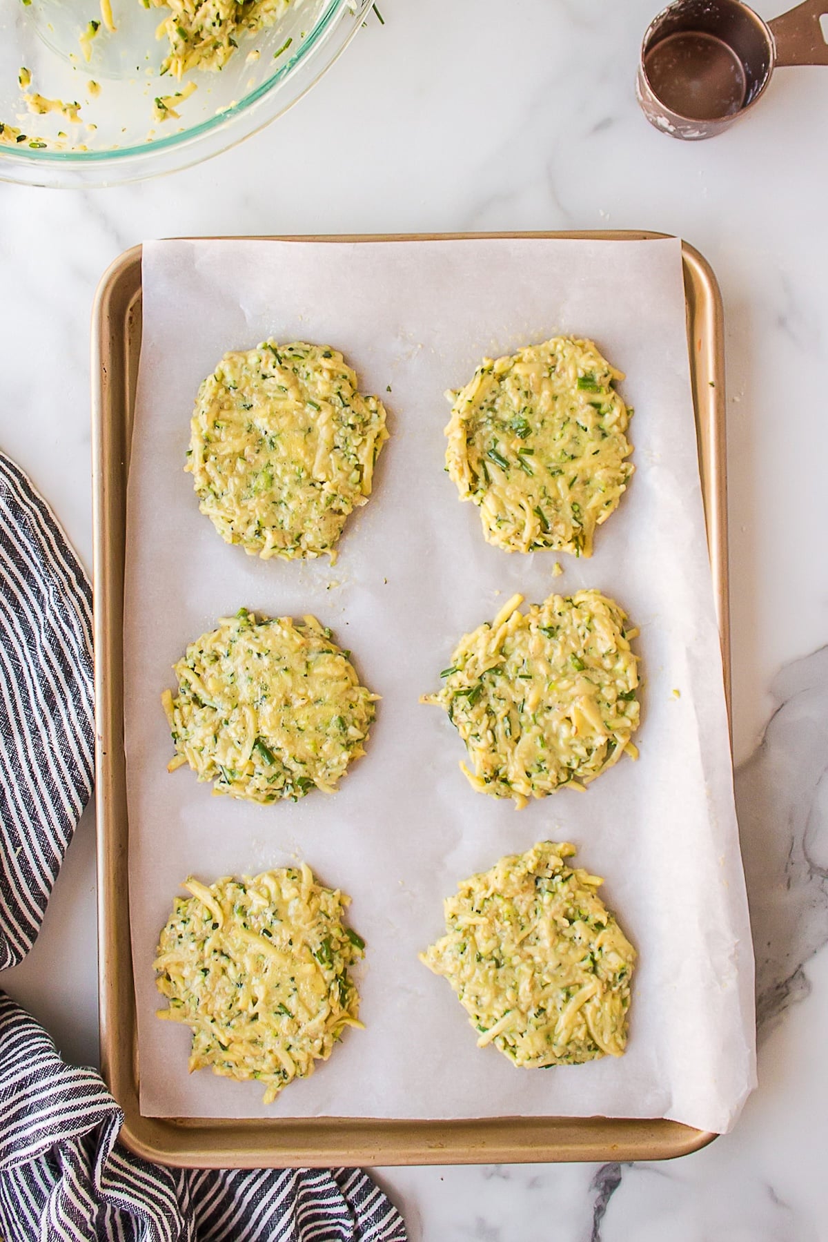 making zucchini potato fritters on baking sheet.