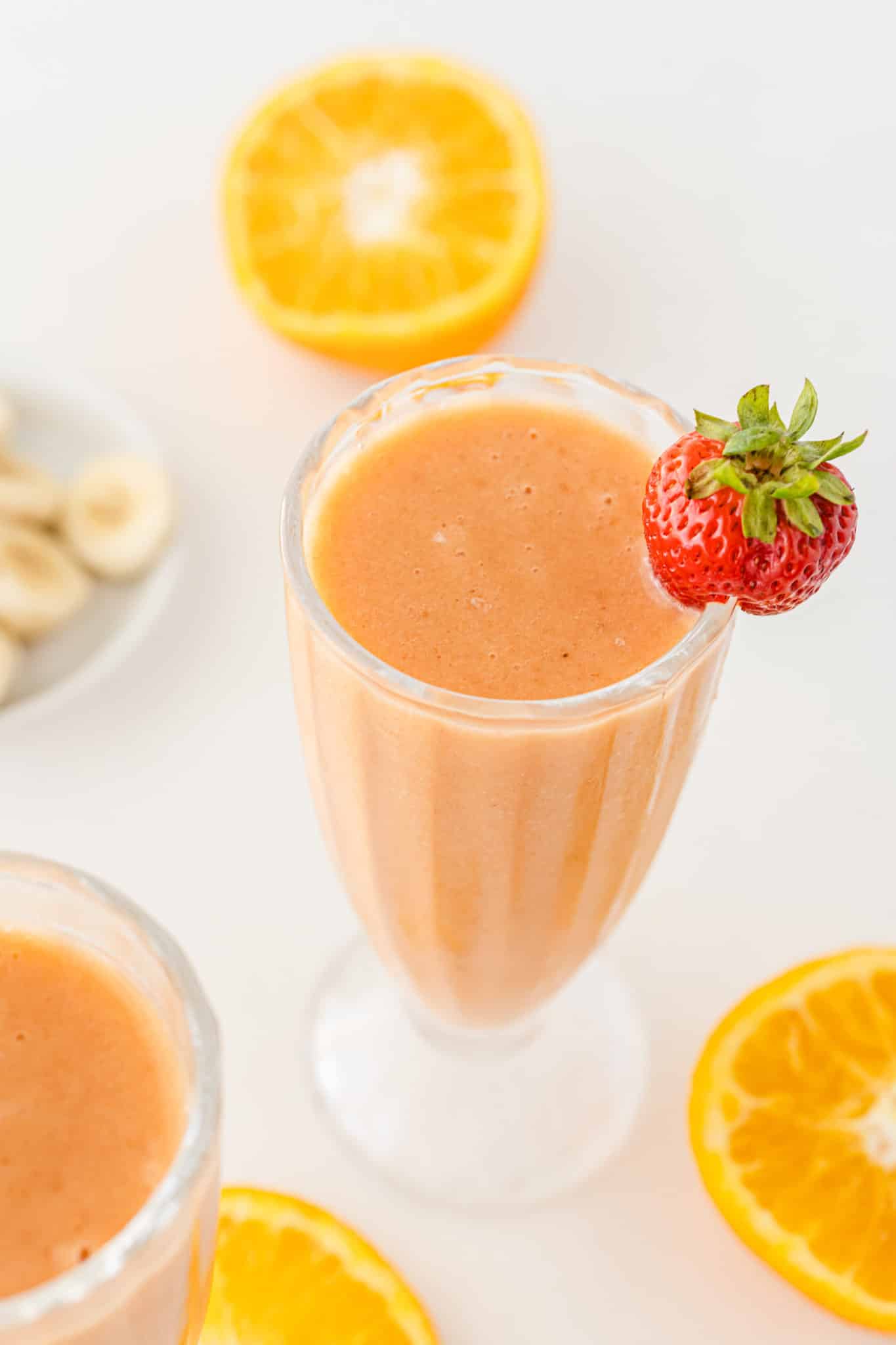 glass of fruit smoothie with a strawberry garnish.