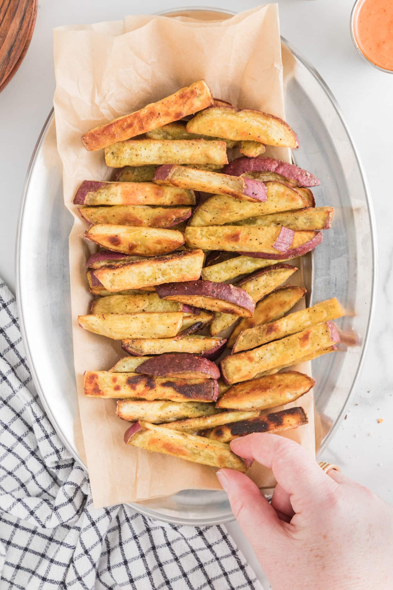 Sweet potato fries on parchment paper in a silver tray.