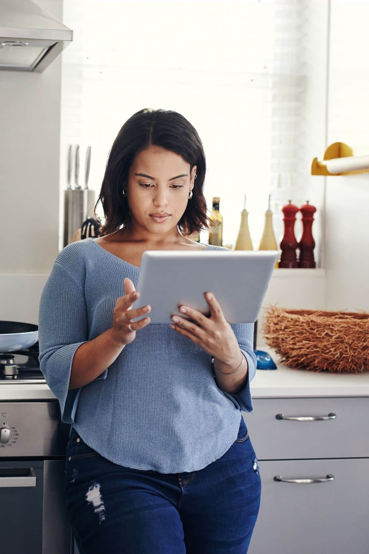 woman meal planning on a tablet in her kitchen.