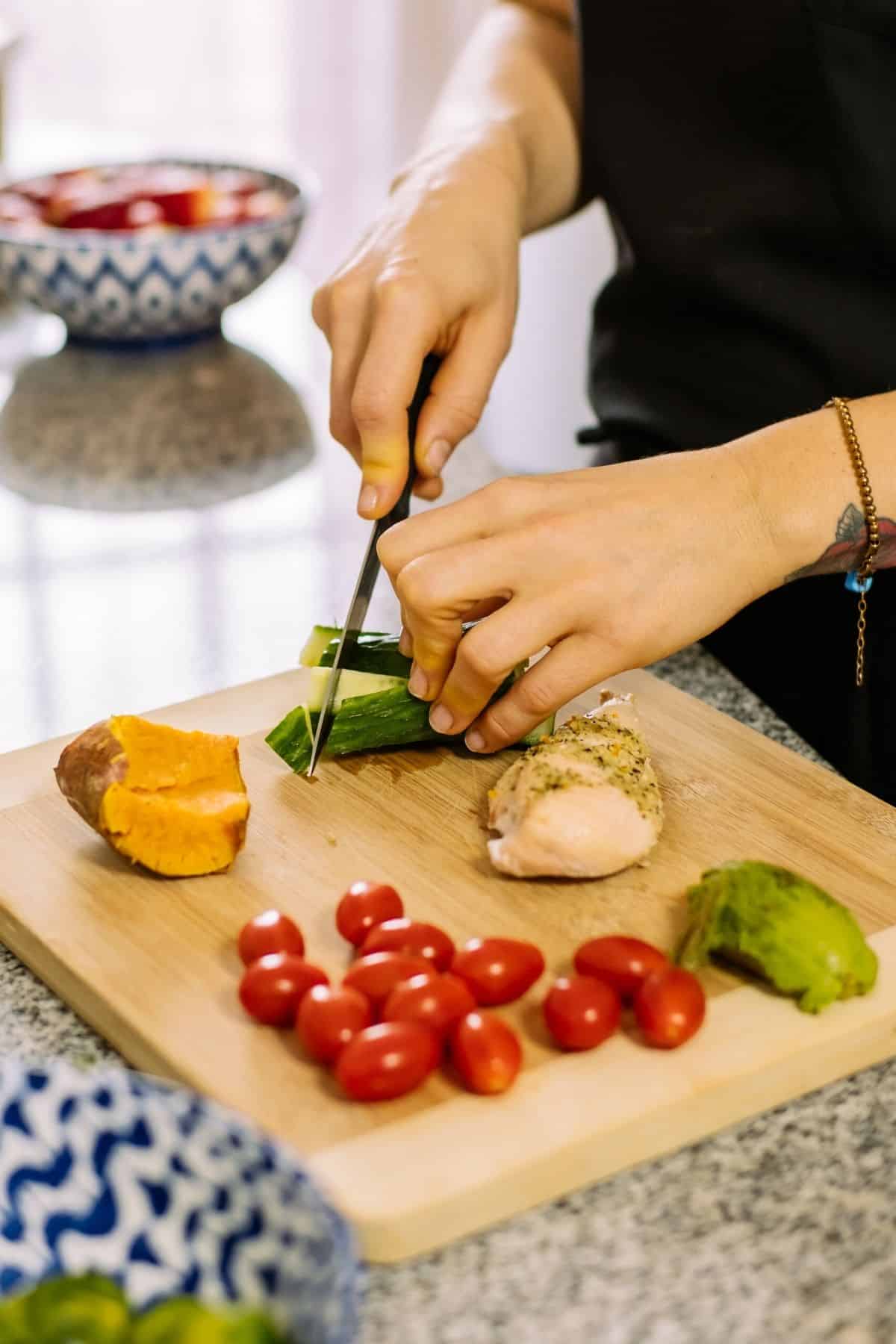 woman  prepping vegetables on a wooden cutting board.