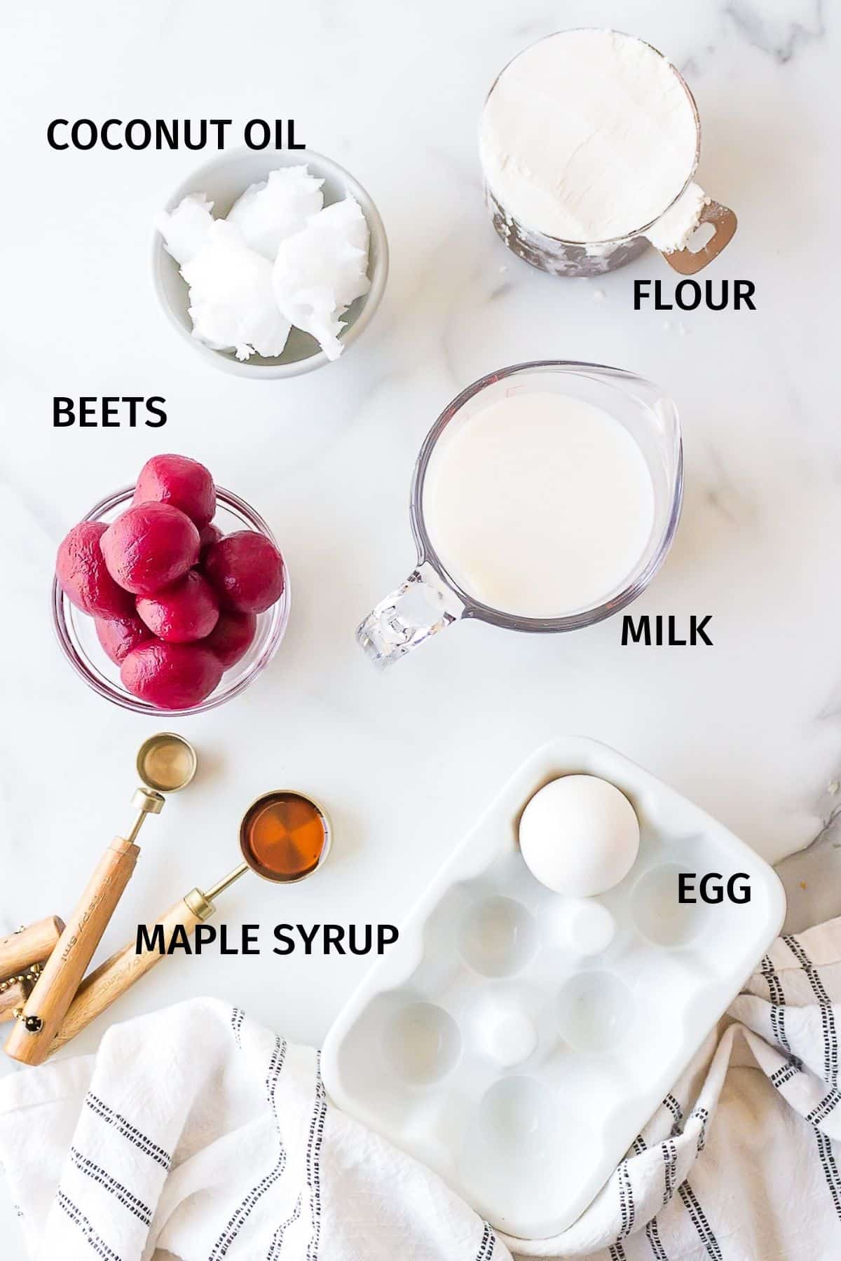 Ingredients for pink waffles in small bowls on a white surface.