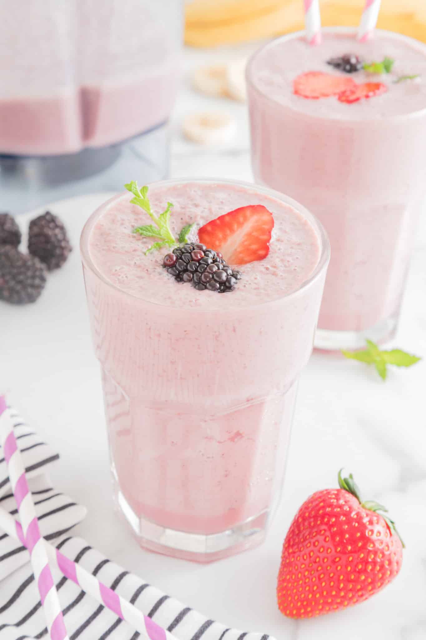A glass of strawberry blackberry smoothie with fresh fruit floating on top.