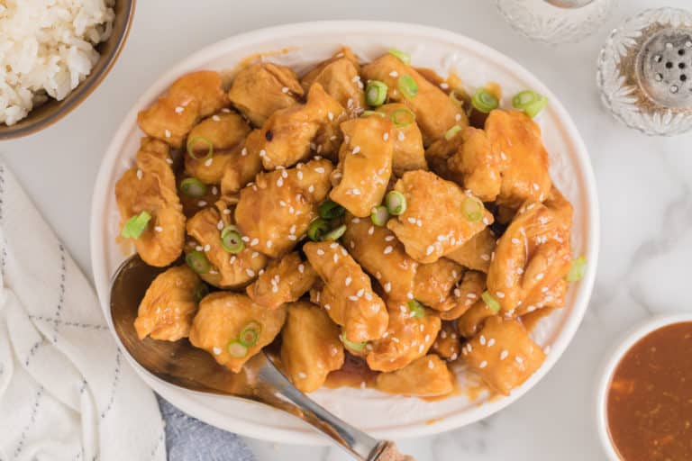 Completed air fryer orange chicken bites topped with sesame seeds and green onions.