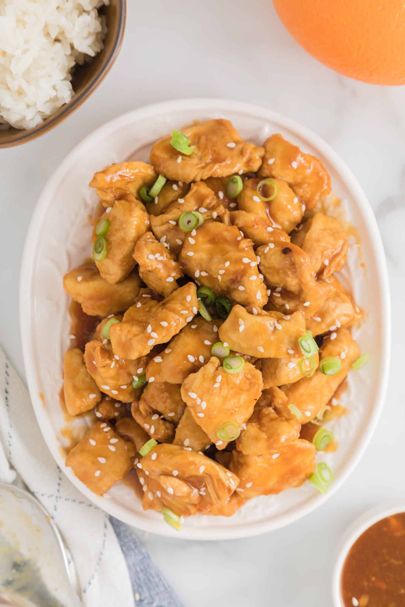 Completed air fryer orange chicken bites topped with sesame seeds and green onions.