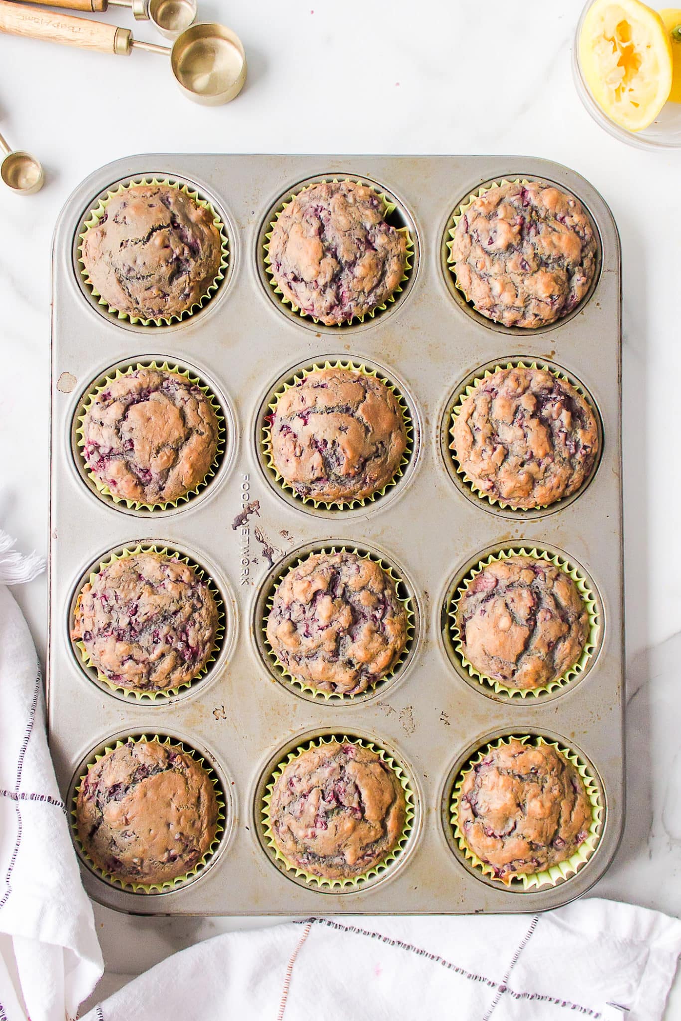 Baked vegan blackberry muffins in yellow papers in a muffin tin.