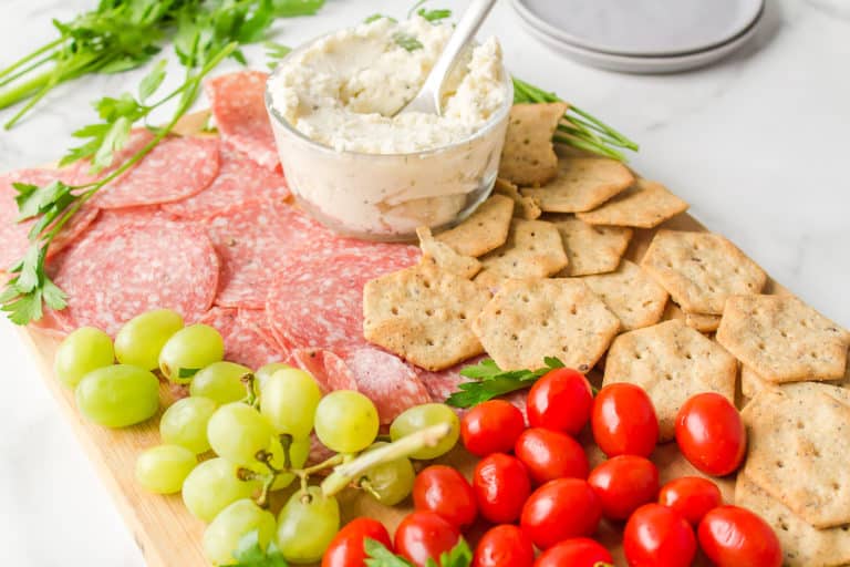 A dairy-free and gluten-free charcuterie board with grapes and tomatoes.