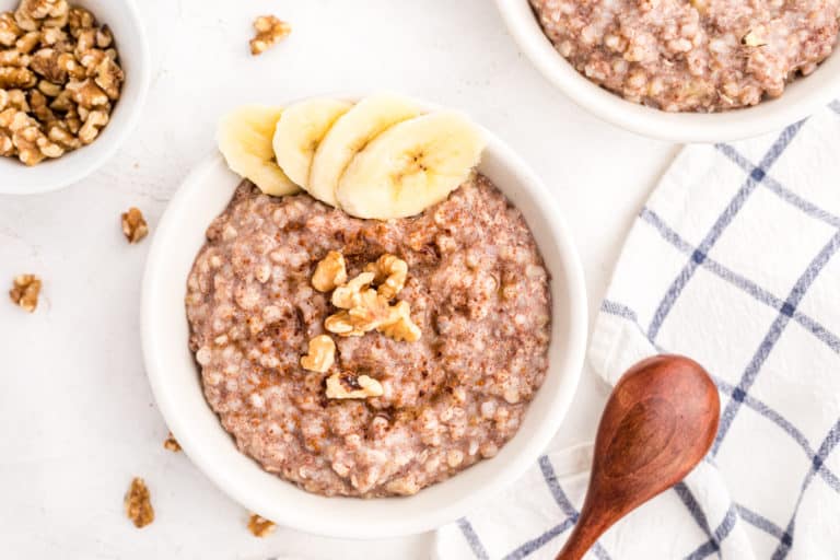 Two small bowls of buckwheat porridge topped with bananas and walnuts.