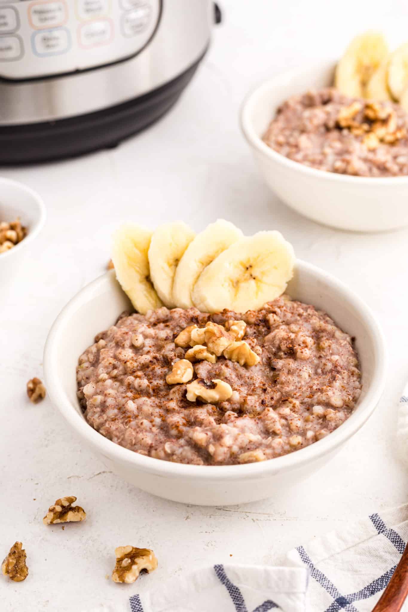 Two small bowls of buckwheat porridge topped with bananas and walnuts.