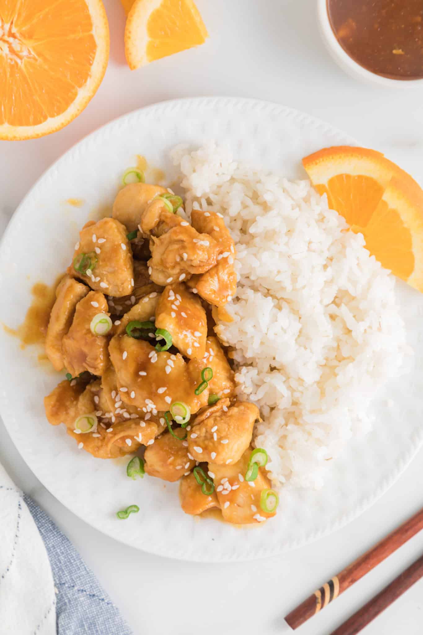 White rice and air fryer orange chicken on a white dinner plate.