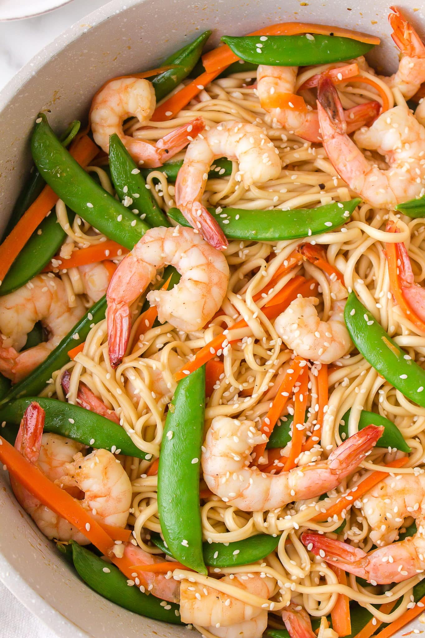 Shrimp udon with peas and peppers in a bowl.