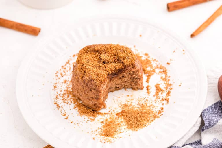 A small snickerdoodle cake with a bite taken from it on a small white plate.