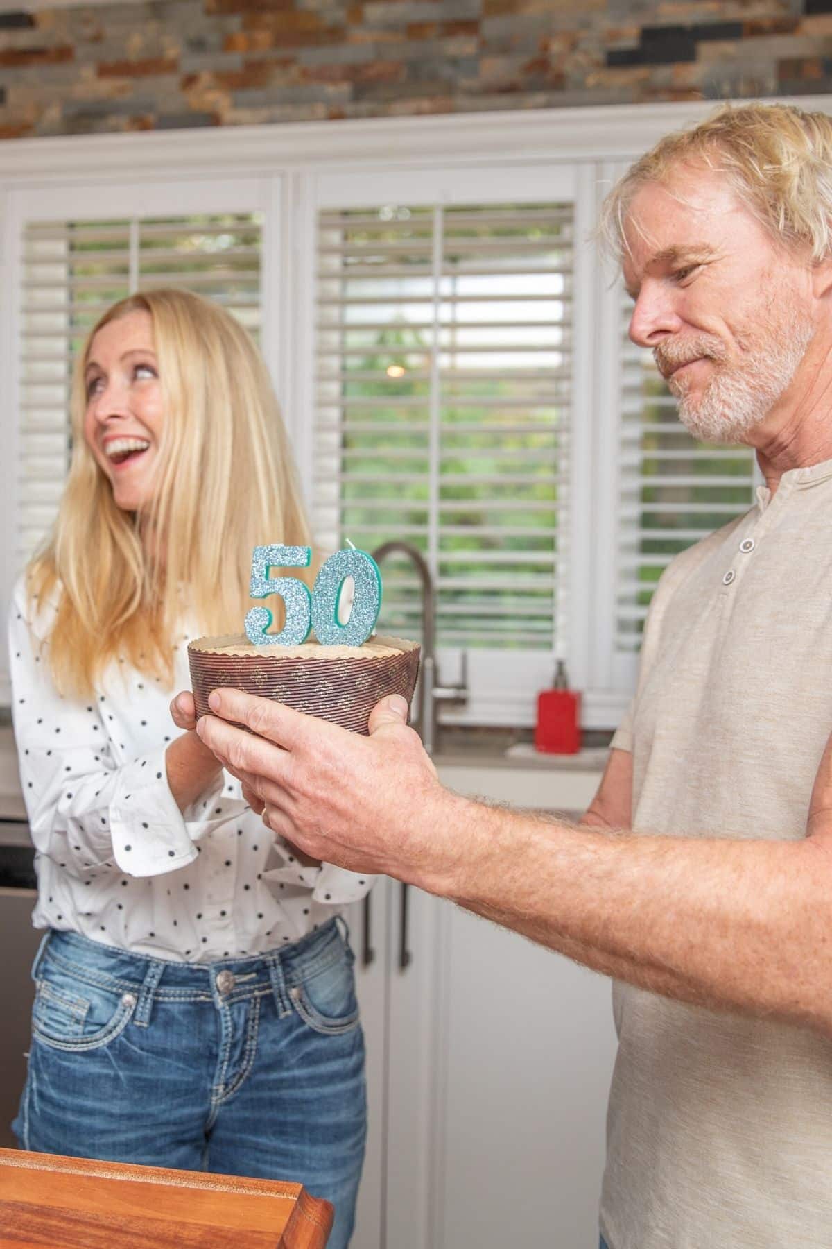 woman holding a cake with 50 on it.