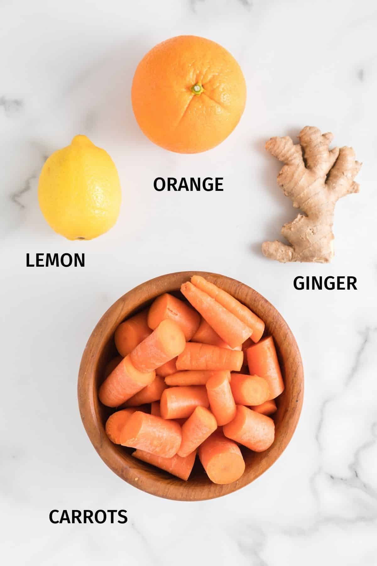 Ingredients for carrot orange juice on a white surface.