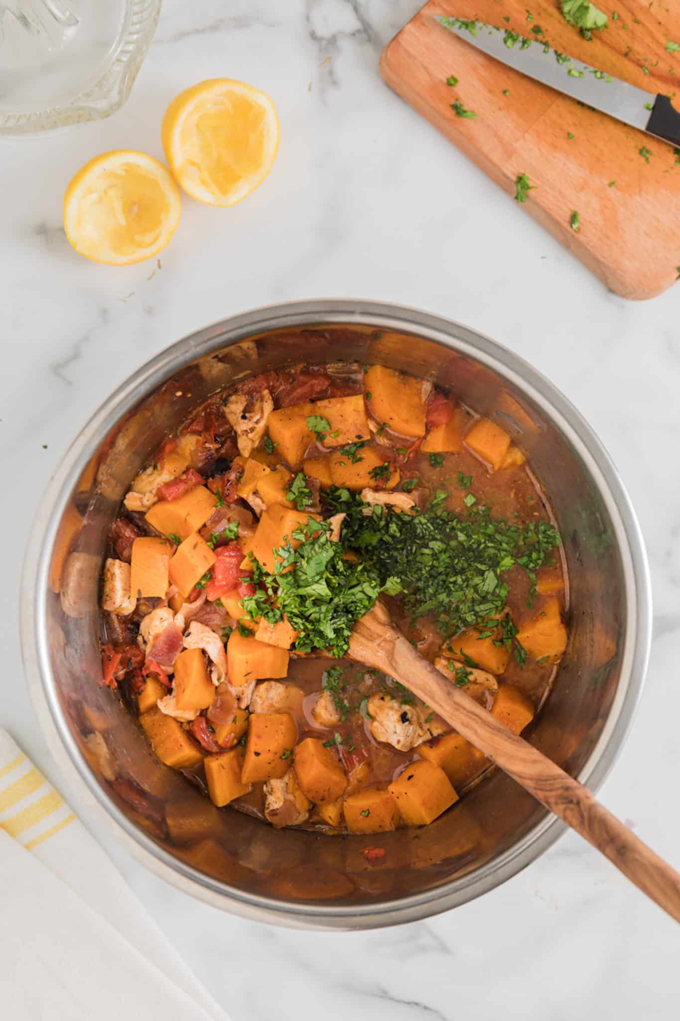 cooked chicken and sweet potatoes in an instant pot with fresh herbs on top.