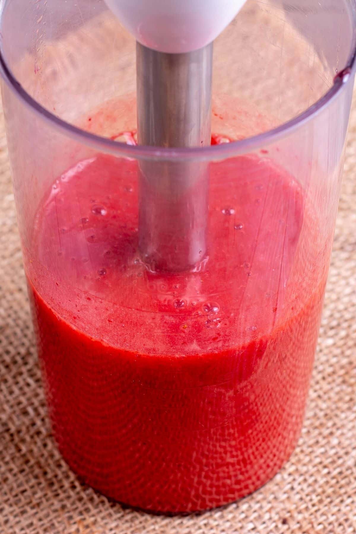 blending strawberries using a hand blender.