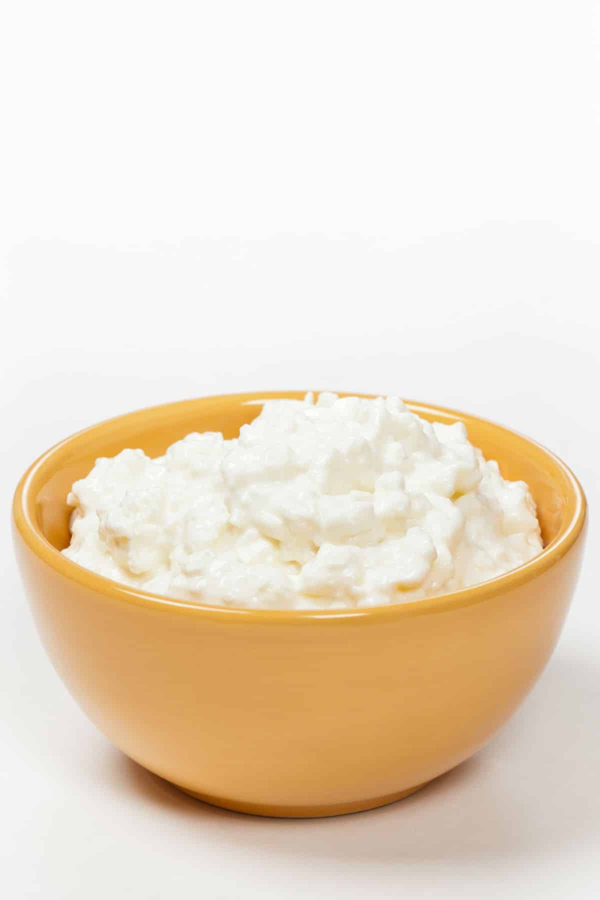 Small yellow bowl of cottage cheese on a white counter.