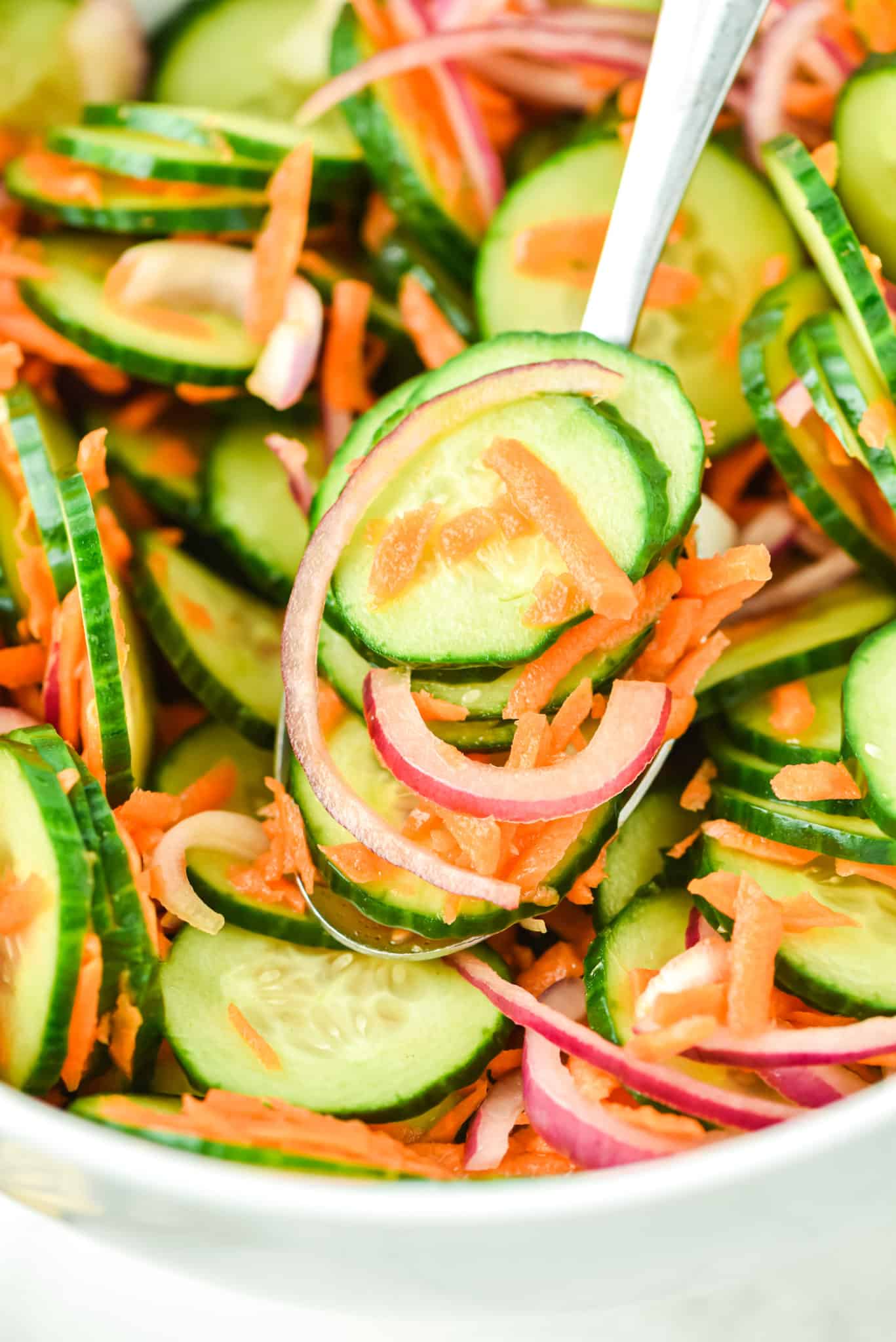 A forkful of cucumber carrot salad over the serving bowl.