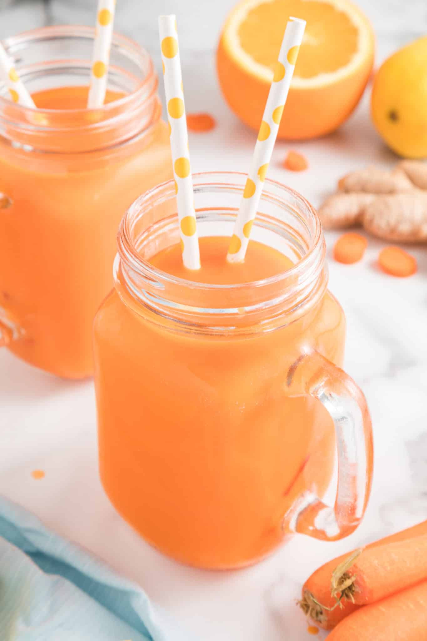 Two mason jar mugs with carrot juice, each has two straws.
