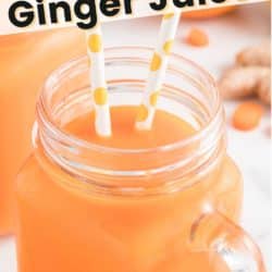 A handled mason jar with two straws filled with carrot juice.